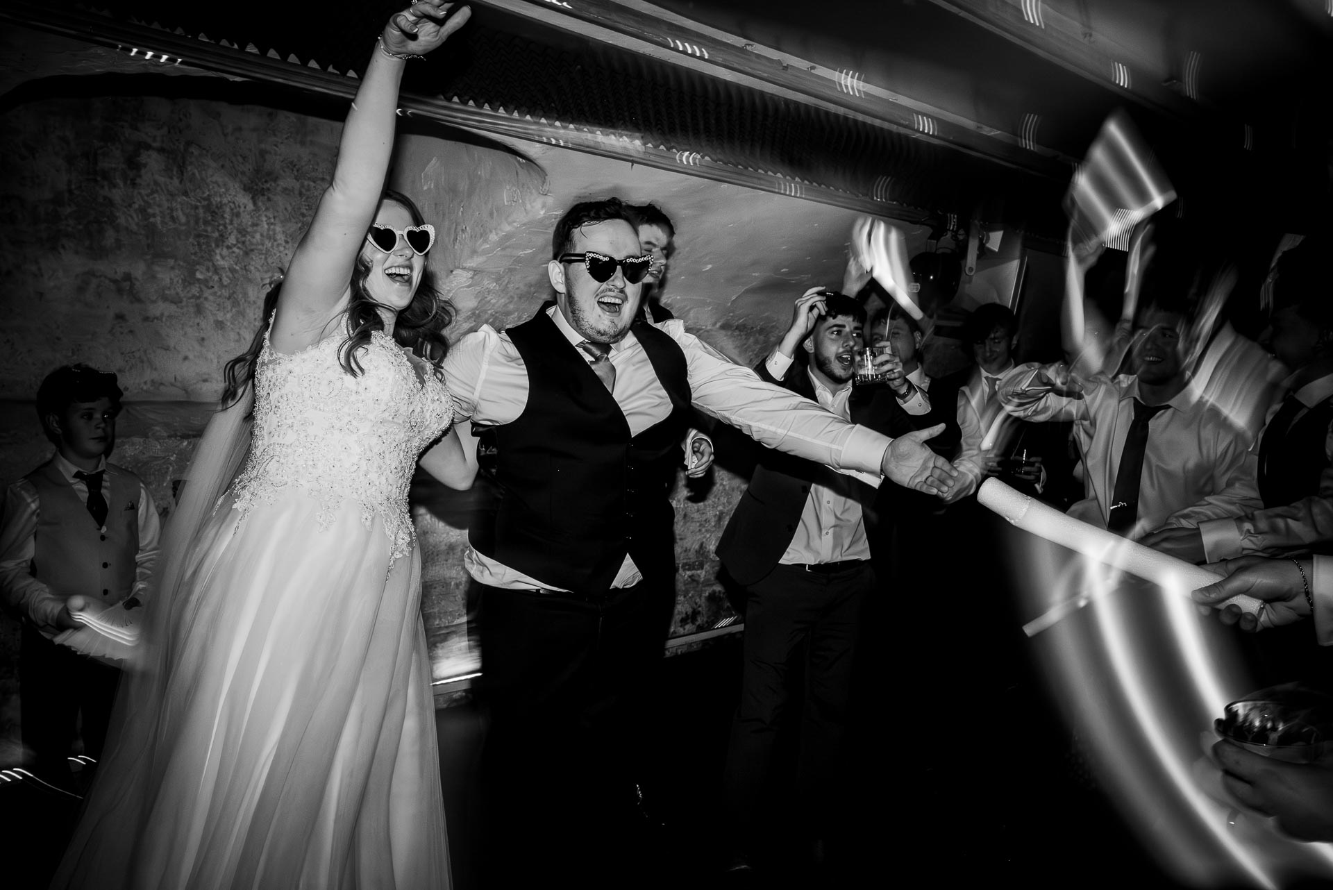 Wedding party in full swing with a bride and groom dancing with sunglasses on a packed dance floor. By Libra Photographic in Dorset