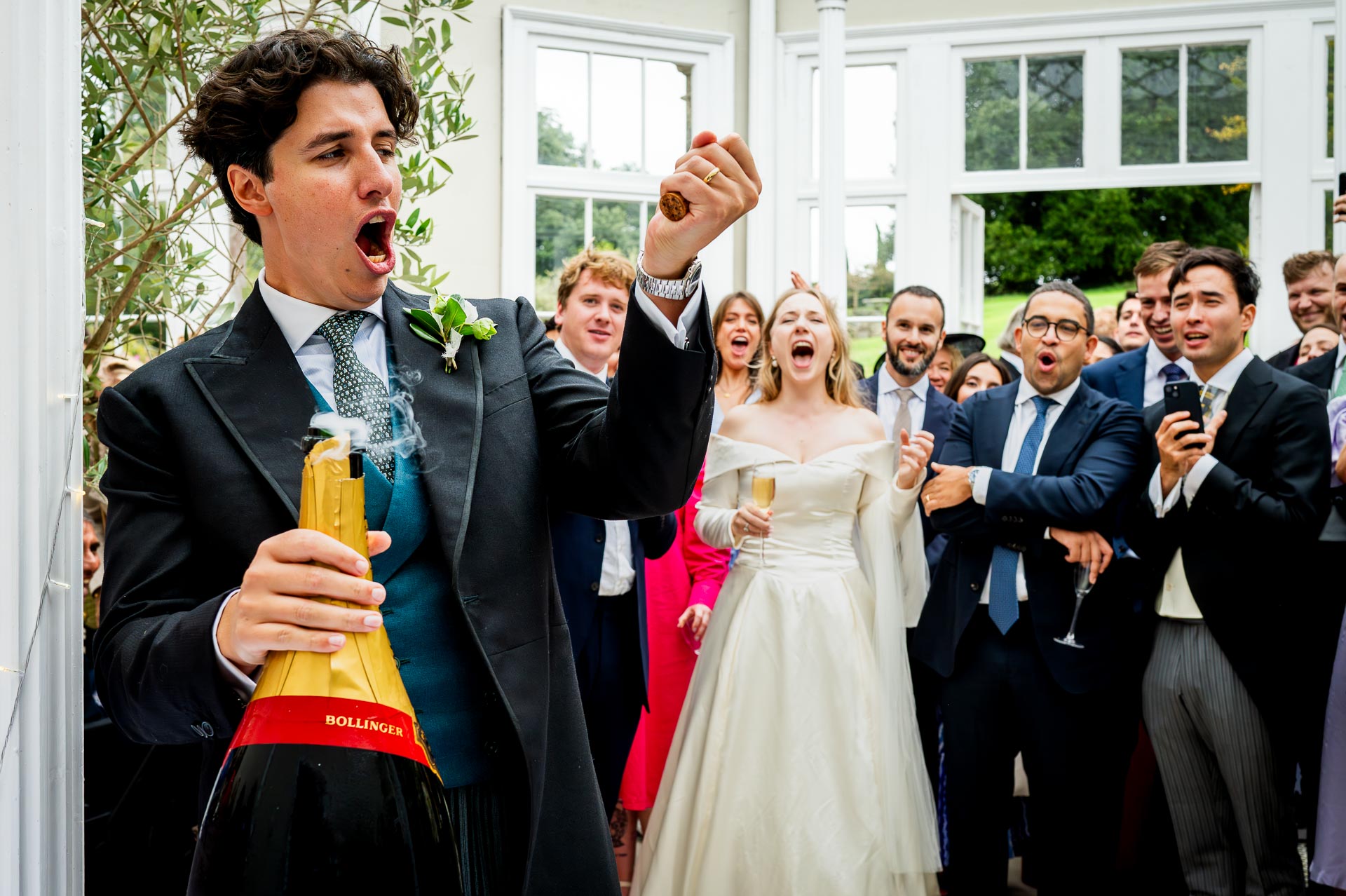 Groom uncorks a massive bottle of champagne at a Dorset wedding. By Libra Photographic