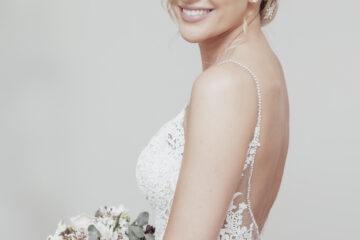 Bride smiling at the camera, holding a pastel bouquet in her hands. By Ross Willsher Photography