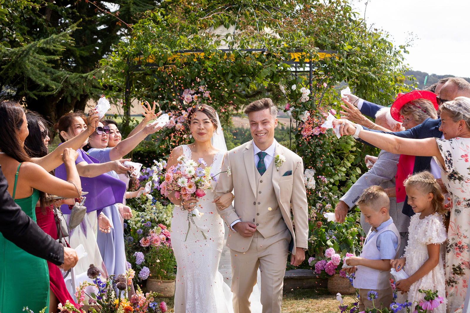 guests throw confetti over a bride and groom outdoors at North Cadbury Court - by photographer Martin Dabek
