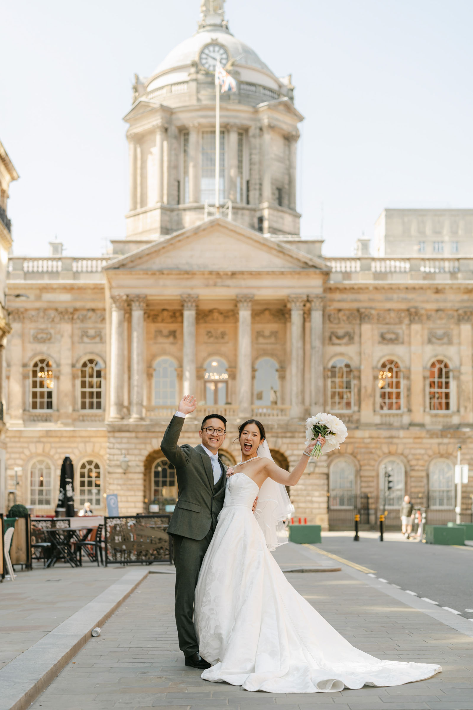 Groom and bride posing outside a historic building in Liverpool by Christy Photography