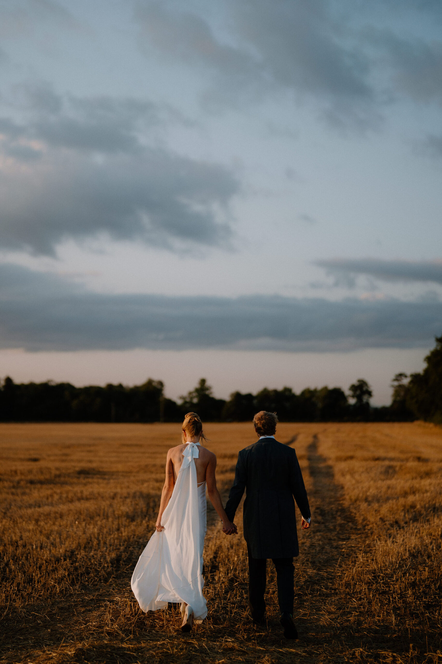 Newlywed couple walking through beautiful countryside just before sunset - Tom Aizenberg Photography