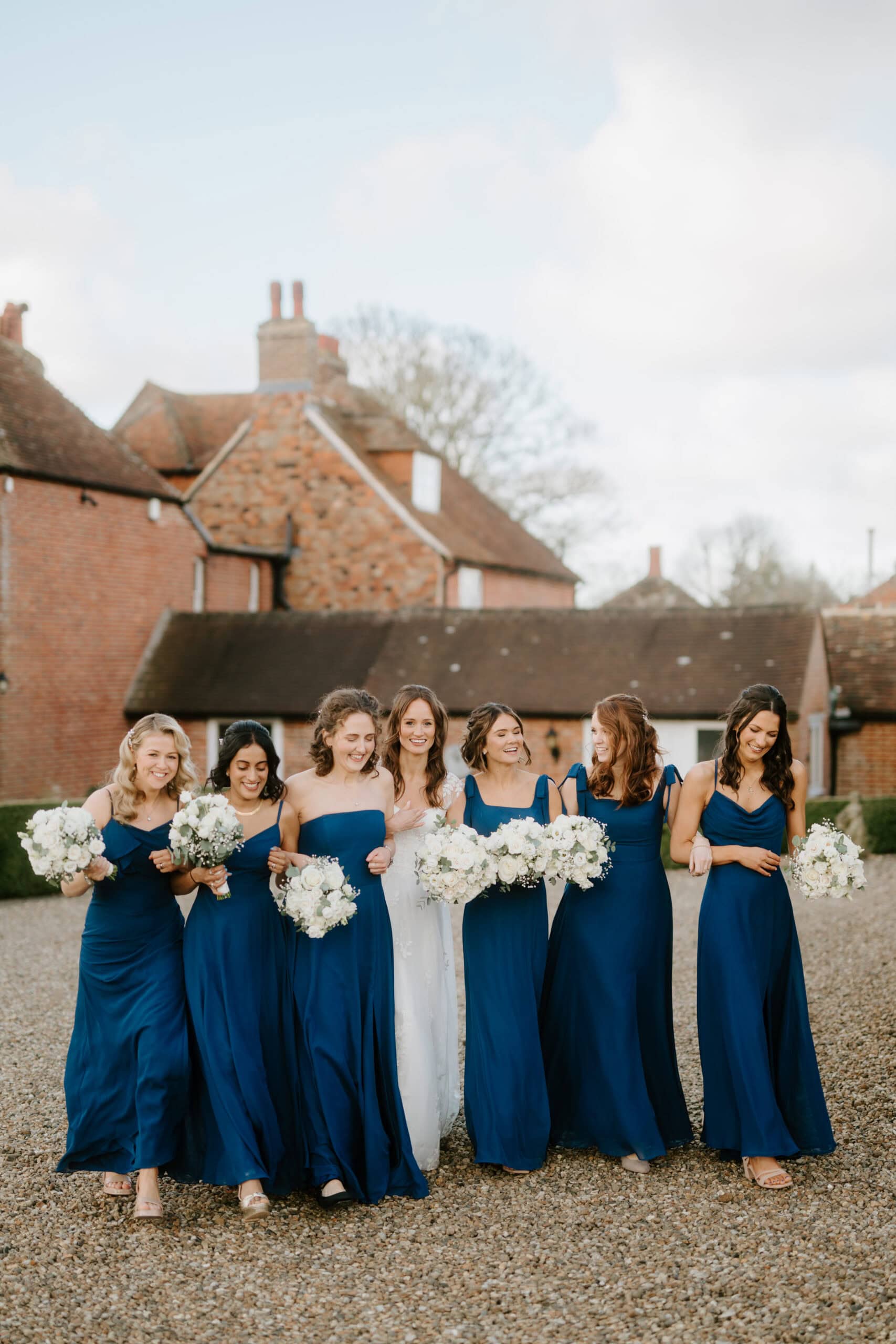 Bride and bridesmaids in rich blue dresses with white bouquets at Winters Barns by Pearce Wedding Photography Kent