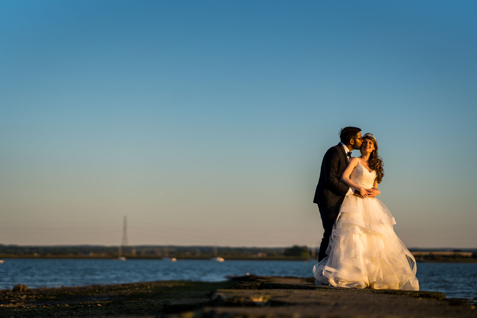 Groom and bride with the sea and sunset sky behind them on the Kent coast by Benjamin Toms Photography from Canterbury