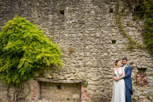 Ancient stone walls at Westenhanger Castle as a bride and groom pose for a portrait - Benjamin Toms Photography | Kent