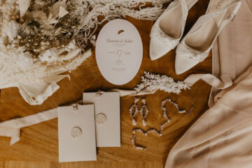 wedding stationery flatlay by Carrie at Honey Bee Mine with bridal jewellery, white wedding shoes and dried flowers, by Capture It