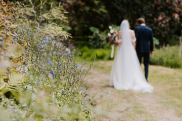 Newlyweds walking away from the camera in the gardens of Carwinion House Falmouth | Cornwall wedding photographer Hannah Timm Photography