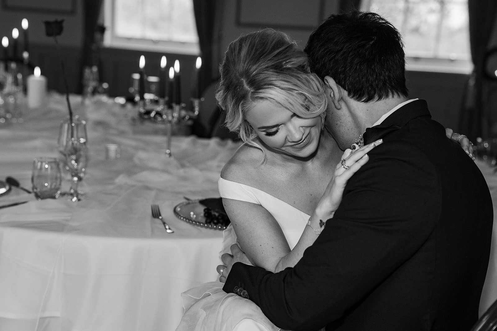 A model bride in the arms of her partner | black and white photo with candles behind | styled by Lauren Batten Events