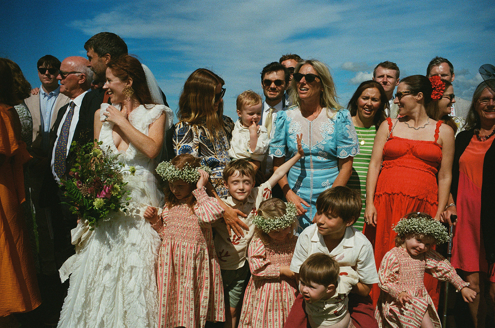 Guests surround the groom and bride at a wedding. It's sunny and the sky is blue - film wedding photography by York Place Studios