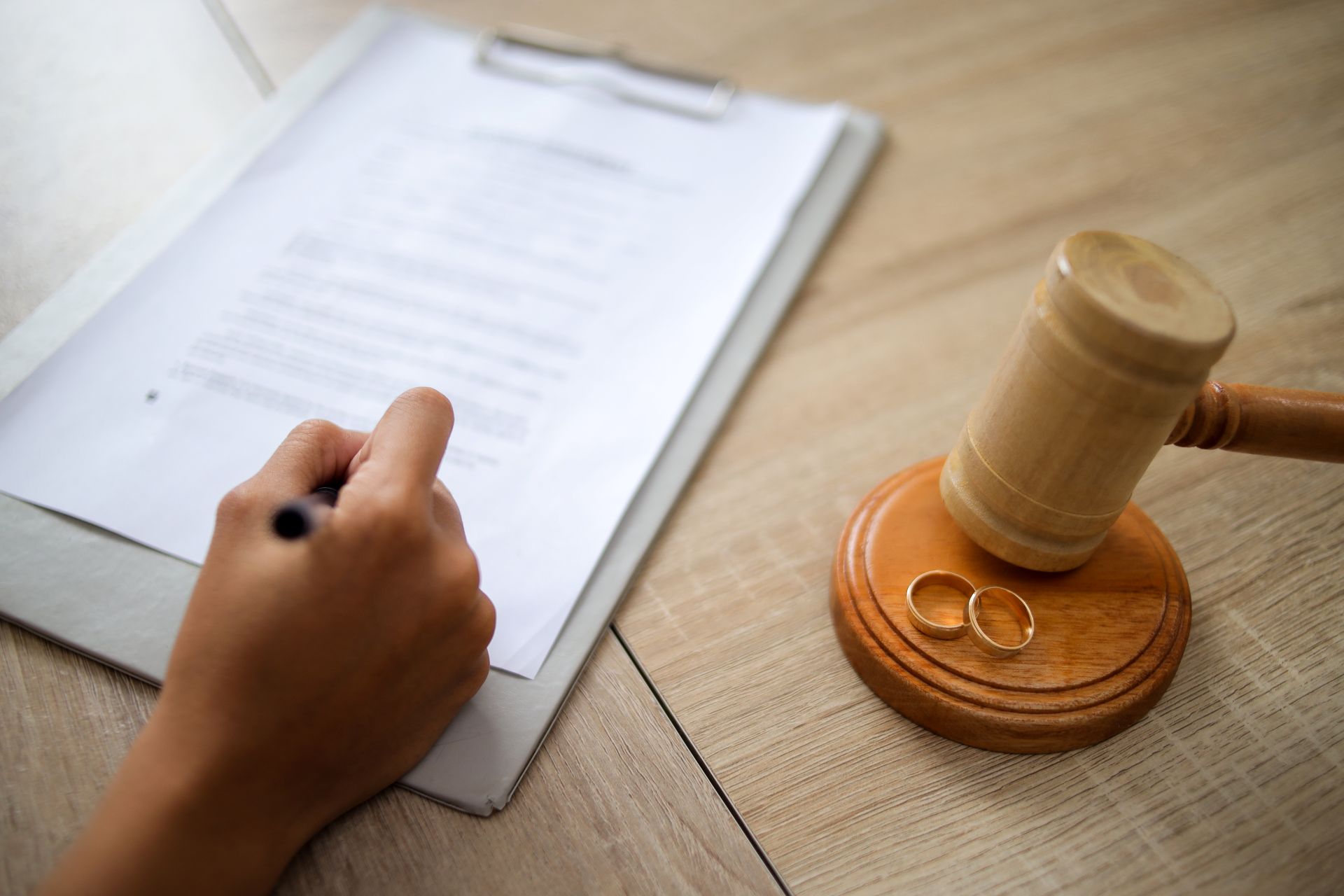 a hand with a pen writing notes in a folder, alongside a gavel