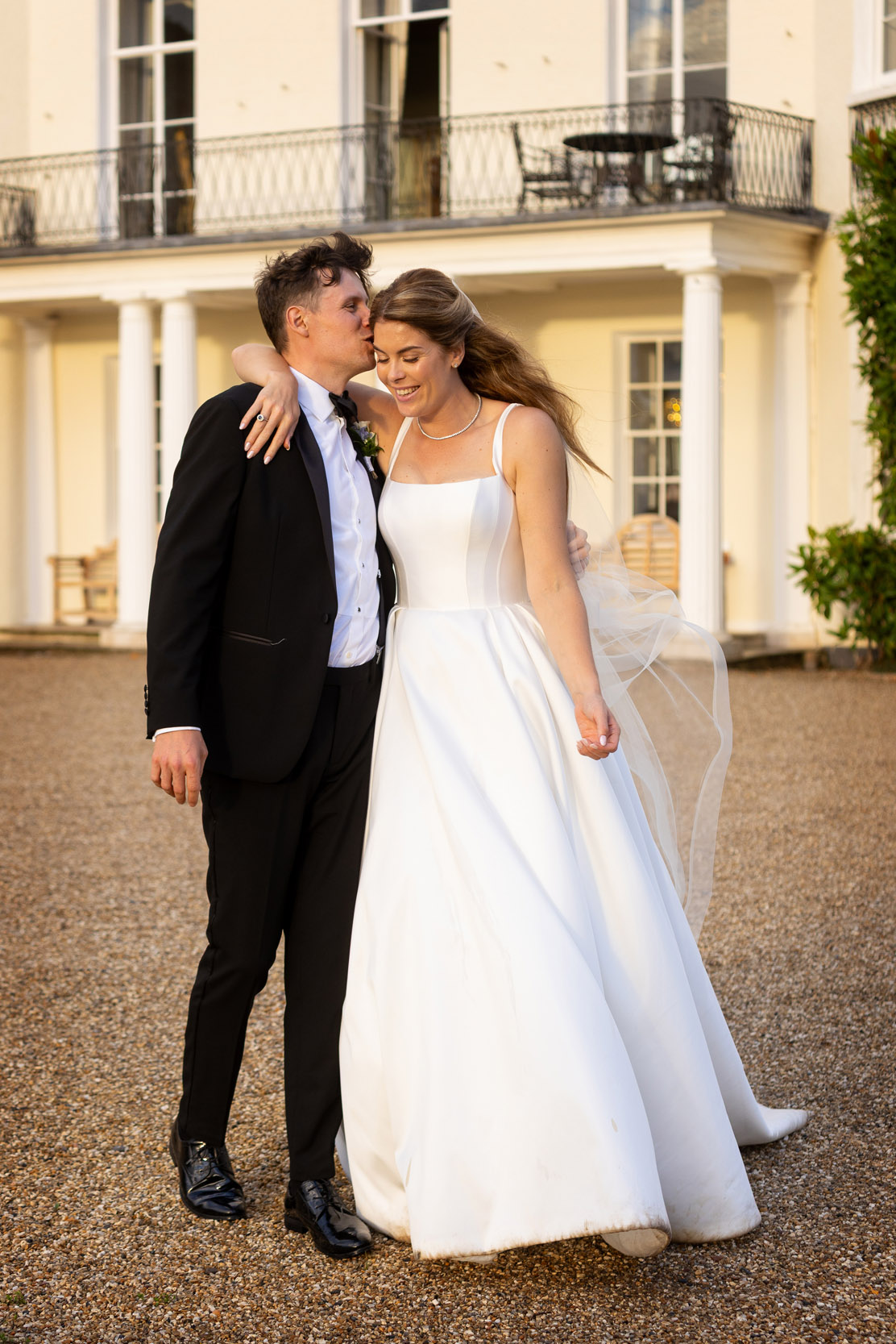 Groom and bride arm in arm outside Rockbeare Manor Devon at golden hour | Martin Dabek recommended photographer