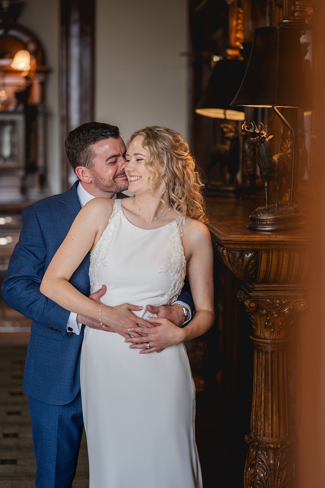 Romantic couple in wedding attire, arms around each other smiling - at Merewood Country House | Jaye Peg Photography Cumbria