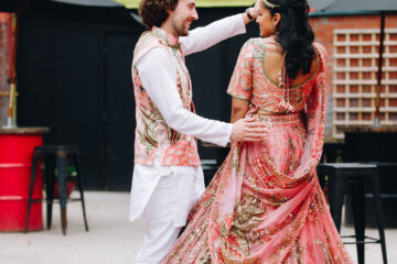 Groom and bride in Indian attire dancing outside a doorway with CLUB written above it in big bold letters | Priti Shikotra Weddings
